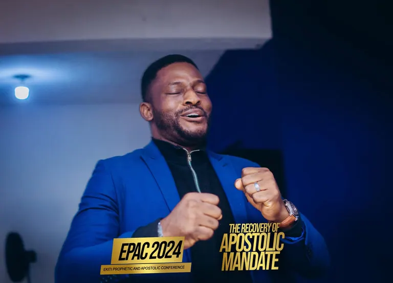 A minister in a blue jacket praying during EPAC 2024