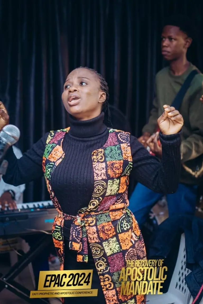 A woman worshipping with a keyboard player behind her at EPAC 2024